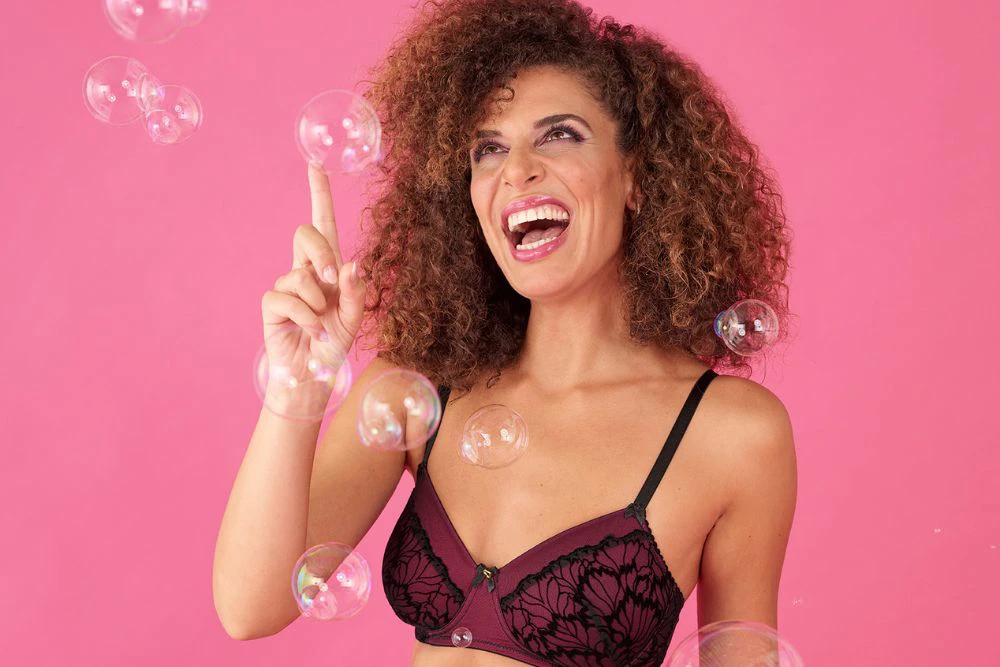 Femme confiante en soutien-gorge souriant et jouant avec des bulles